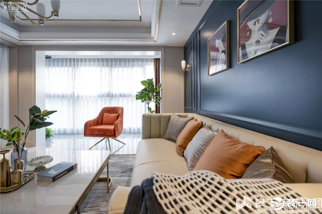藏蓝色的护墙板背景墙时尚大气,搭配米白色的家具和爱马仕橙的抱枕和