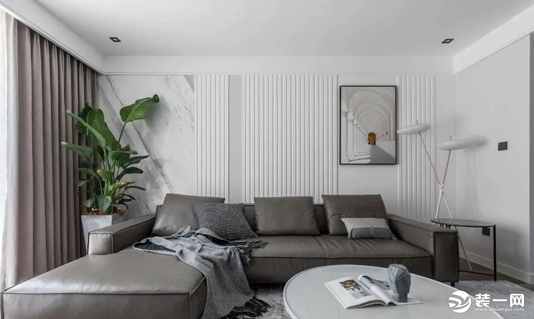 灰色皮沙发与窗帘色调呼应，背景采用石材和竖线条构成，利用竖线条拉伸视觉层高