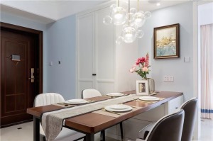 简单的餐桌椅放在了沙发的背后，淡蓝色的墙面搭配一幅挂画，还有上方的创意玻璃吊灯
