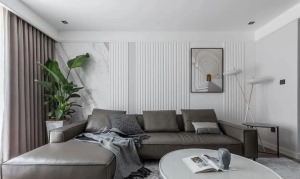 灰色皮沙发与窗帘色调呼应，背景采用石材和竖线条构成，利用竖线条拉伸视觉层高