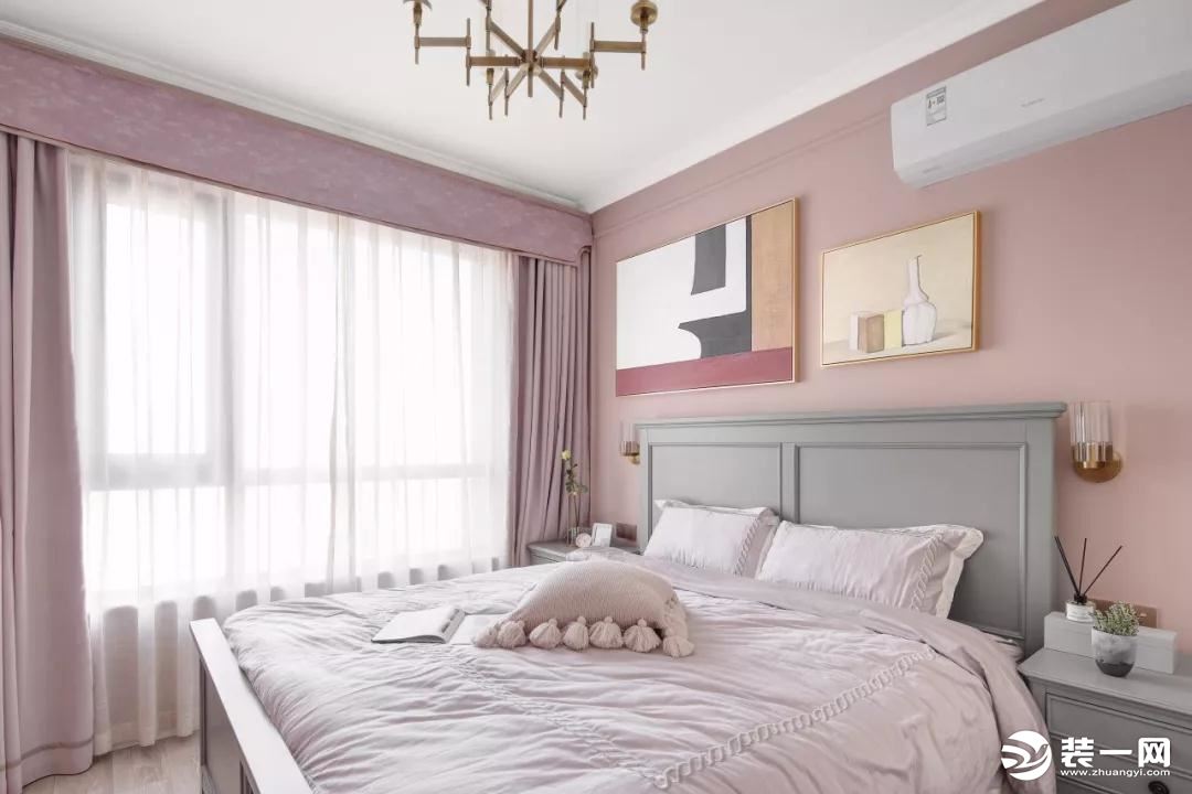 主卧以粉色调为主，床头背景墙挂了两幅格调装饰画，搭配一张浅灰色的美式实木床，营造出柔和唯美的浪漫感。