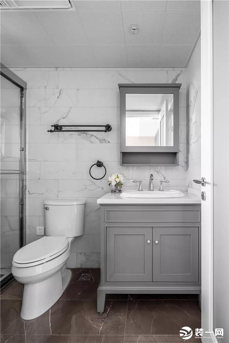 卫生间使用白色大理石墙面，搭配浅灰色浴室柜，自然而清冽。壁柜式梳妆镜一物两用，开放式的储物格方便洗漱