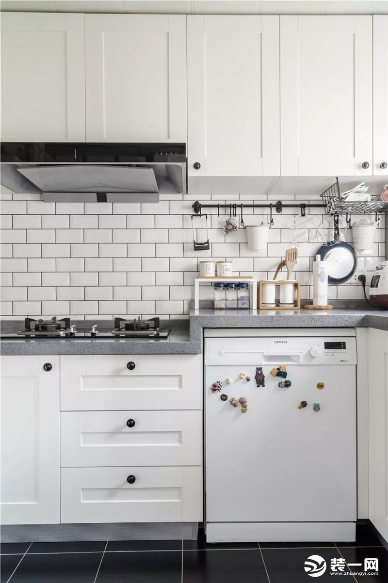 厨房墙面的小白砖和白色橱柜，搭配黑色的地砖，显得时尚又大方。而墙面的挂钩架和嵌入式的厨电收纳，又让厨