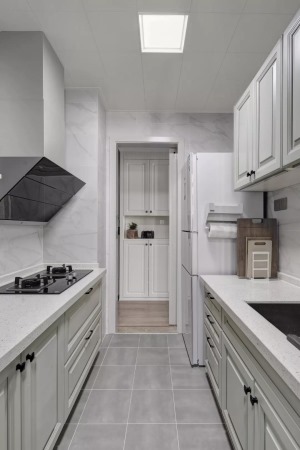 厨房地面铺设灰色哑光砖，墙面铺设大理石纹瓷砖，搭配上灰白色的橱柜，让做饭的空间显得干净而优雅。