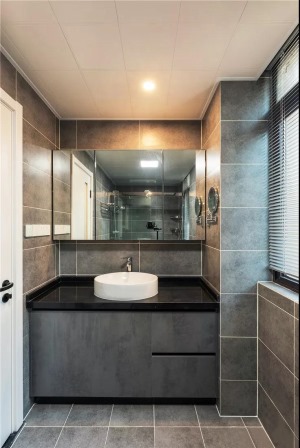 卫生间以深灰色瓷砖为基调，辅以白色美缝使空间更有层次，浴室柜采用黑色大理石台面增添高级质感，整体以柔