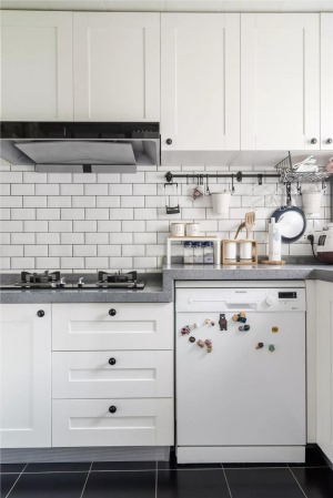 厨房墙面的小白砖和白色橱柜，搭配黑色的地砖，显得时尚又大方。而墙面的挂钩架和嵌入式的厨电收纳，又让厨