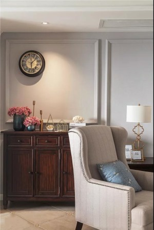 沙发一角利用墙面与收纳柜形成的角落空间，放置了经典的美式斗柜，辅以墙面复古钟表及精致的装饰摆件，优雅