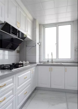 厨房选用了白色为主色调，构造一个纯净明亮的空间。大理石纹路的墙地砖简约而清冽，金属色橱柜把手为空间带