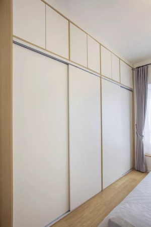 入墙式的整体衣柜，推拉式的柜门节省了活动空间。白色原木的质感让卧室看起来十分小清新。