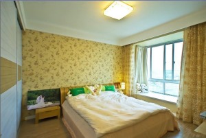 【卧室装修效果图】卧室墙面选用浅黄色翠花墙纸装饰，一进门就设计一个嵌入式的移门衣柜，空间的流畅性也不