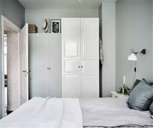 一侧墙面放置了两张高度不一的衣柜，其中左侧的草灰色衣柜与墙壁视觉上融为一体；等到打开门将衣柜遮住时，