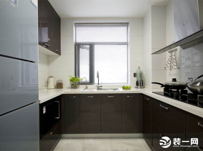  厨房采用现代的黑褐色柜体加不锈钢简约把手与白色的背景瓷片相互搭配，使现代感得以体现。