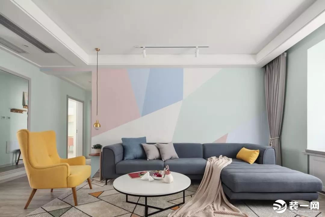 深蓝色的布艺沙发，沙发背景墙设计成了几何形状，旁边墙面还有金属质感的壁灯，显得充满了轻奢气质的氛围感