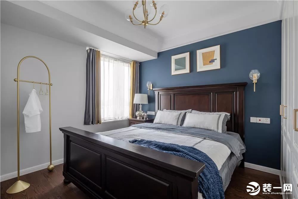 主卧室的床头背景墙被刷成了深蓝色，搭配这款深木色的床，卧室给人一种复古感。床头两侧的壁灯非常有趣，床