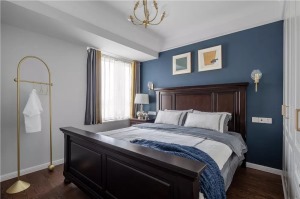 主卧室的床头背景墙被刷成了深蓝色，搭配这款深木色的床，卧室给人一种复古感。床头两侧的壁灯非常有趣，床
