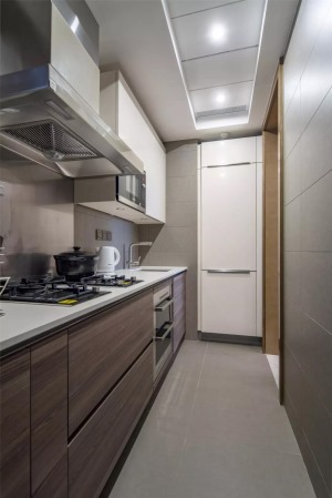 厨房的面积不大，还是一个狭长的空间，所以橱柜也是一字型的布局方案，设计师把冰箱嵌入到墙内，看起来更为