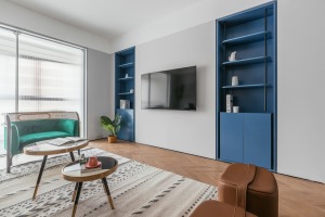 电视背景墙延续简约的风格设计，内嵌式蓝色储物柜特意设计成对称样式，达到平衡整个区域重心的目的。纯色以