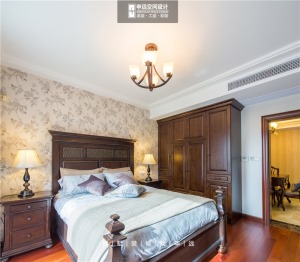 次卧大面积花色墙纸的运用，柔化了床铺的刚硬线条，搭配造型经典的美式台灯，点醒了空间。