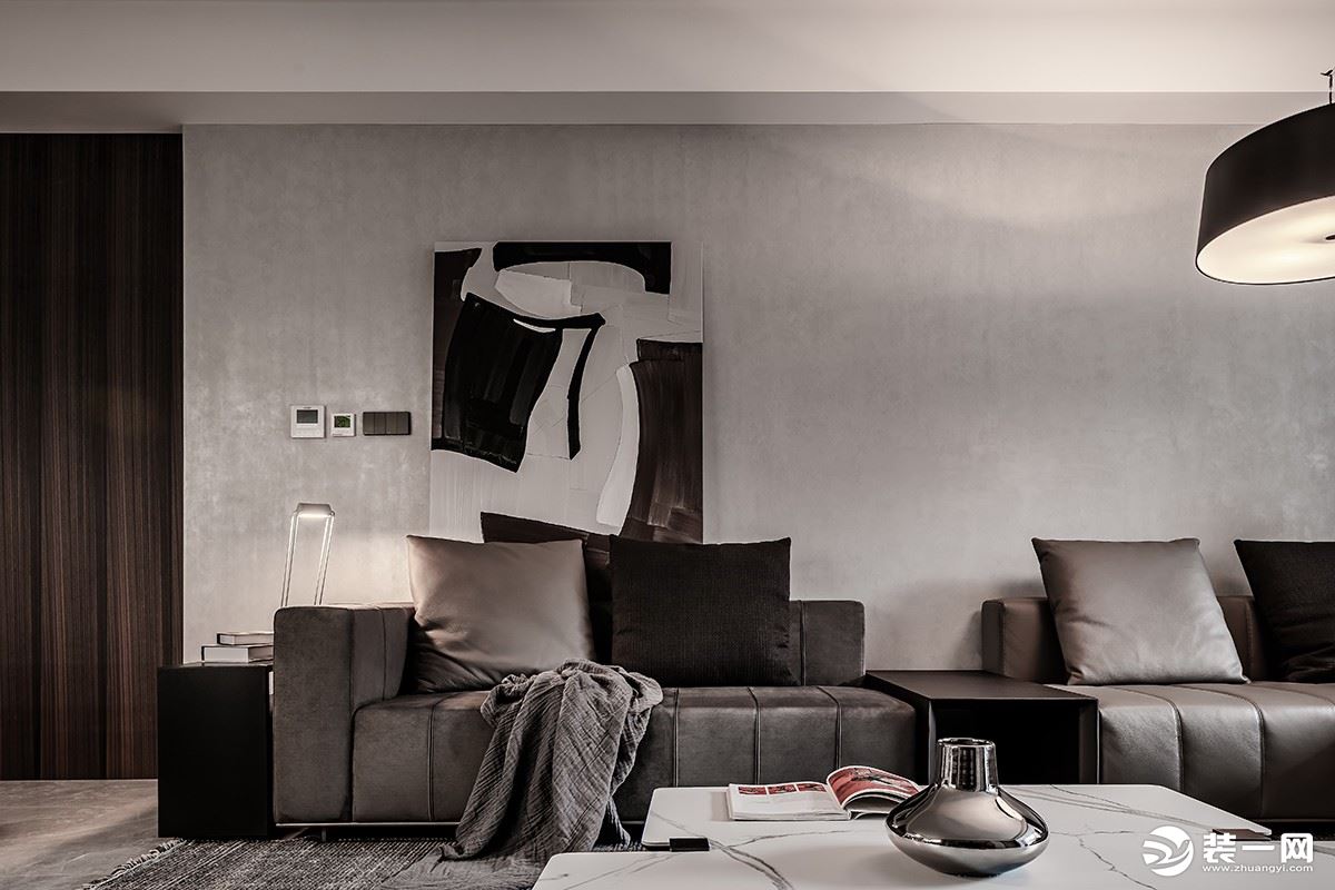 客厅以浅灰色背景墙，柔和的沙发，垂落的灯饰，以暖黄色的灯光，带来温暖与放松的氛围感。