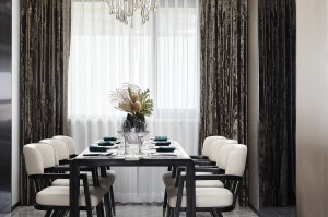 餐厅右侧墙面使用木饰面与灰镜的组合，增加空间面宽及通透感，软装材质和色彩与客厅呼应，翠绿点缀于餐桌之