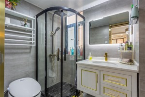 卫生间墙地面通铺同色系瓷砖，搭配白色卫浴与黑色五金，黑白对比色的视觉层次清晰。自带光源的智能式浴柜镜