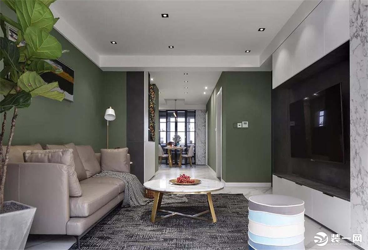 而沙发背景墙是延续了整体的复古绿色，皮质的沙发搭配大理石加金属的茶几，一个多彩的脚凳作为点缀，