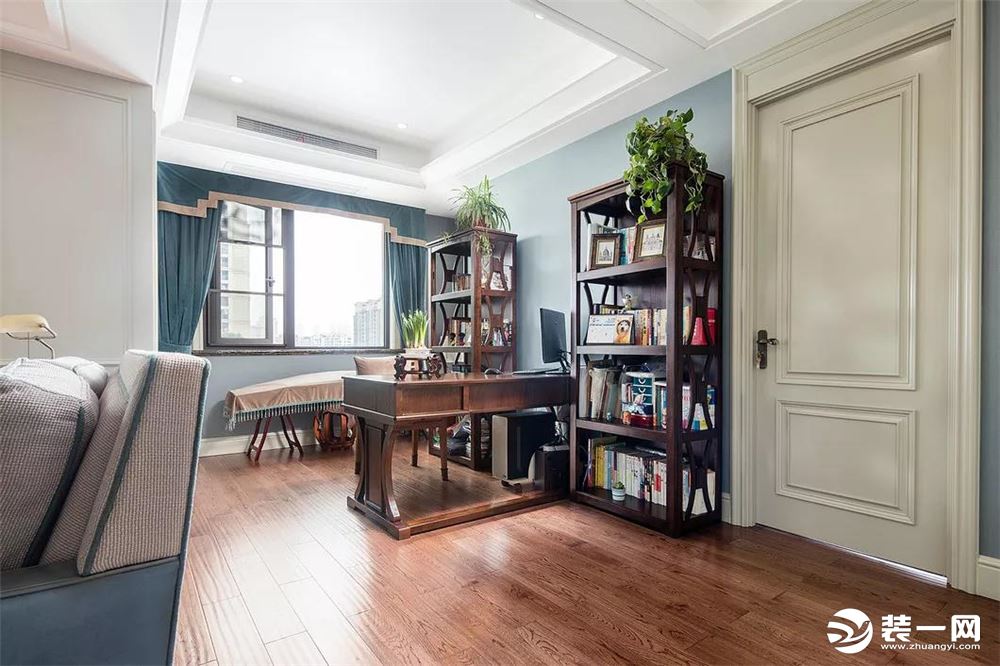 开放式的书房设在客厅沙发后，一张实木书桌与2个书架，摆满书籍与绿植的点缀，在淡蓝色的墙面搭配下，给人