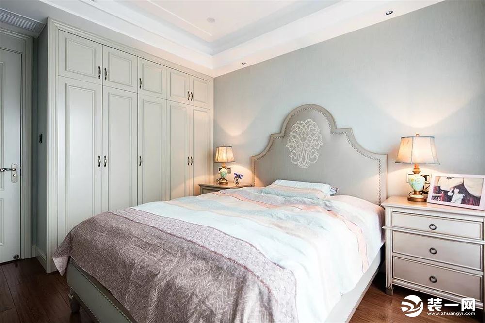 卧室在淡蓝色的墙面下，淡淡的薄荷绿衣柜，搭配上温馨优雅的床单，还有两盏床头台灯，整个空间都给人以温馨