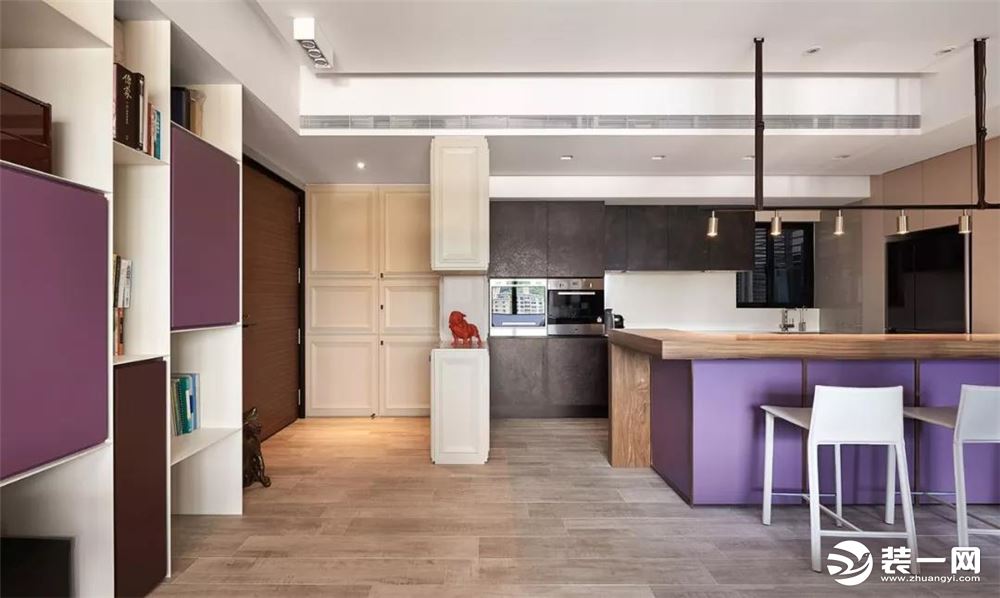 ▲开放式的餐厨布局，餐桌是木色台面+紫色底座的配合，搭配简单的餐桌椅，结合吊架式的一排吊灯，显得特别
