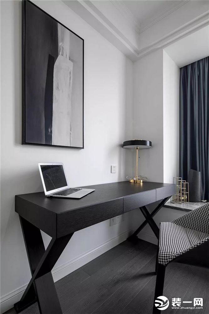 ▲次卧床尾是一个黑白格调的书桌空间，搭配一盏铜艺台灯和一幅黑白抽象画，显得简约明快之余又不乏精致魅力