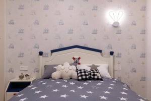 ▲床头墙是浅蓝色的船队航行图壁纸，搭配一盏兔耳床头壁灯，铺上一款满满繁星的被单，以云朵、蝴蝶结的抱枕