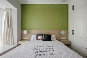 ▲对称的卧室布局，床头墙做了原木的护墙板，搭配茶绿色的墙面，以右侧整墙的衣柜作为收纳，显得实用又满载