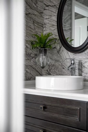 ▲卫生间墙面是灰色调的纹理砖，充满高档大雅的质感美。而深木色的浴室柜有做旧的痕迹，配合白色的卫具，带