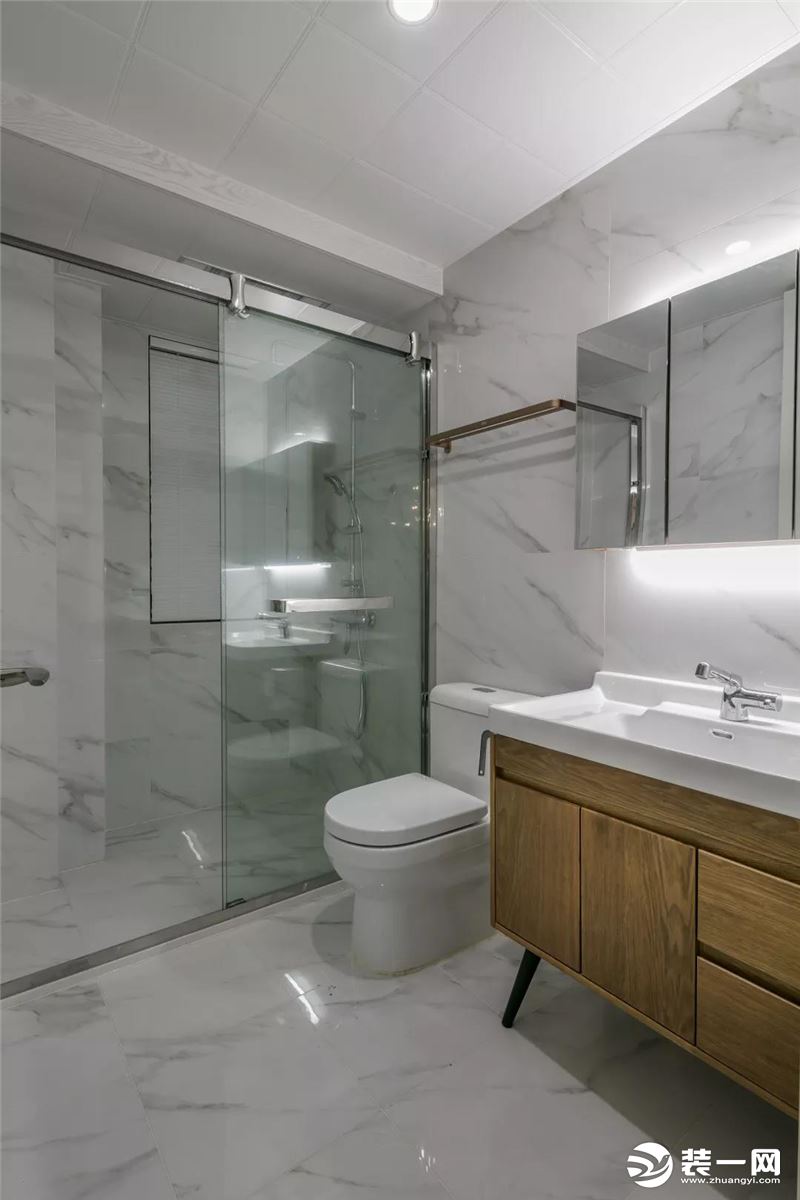 客卫以爵士白的墙面地面，玻璃隔断了淋浴区域，结合木质洗手盆柜，带来的是稳重优雅的卫浴空间。
