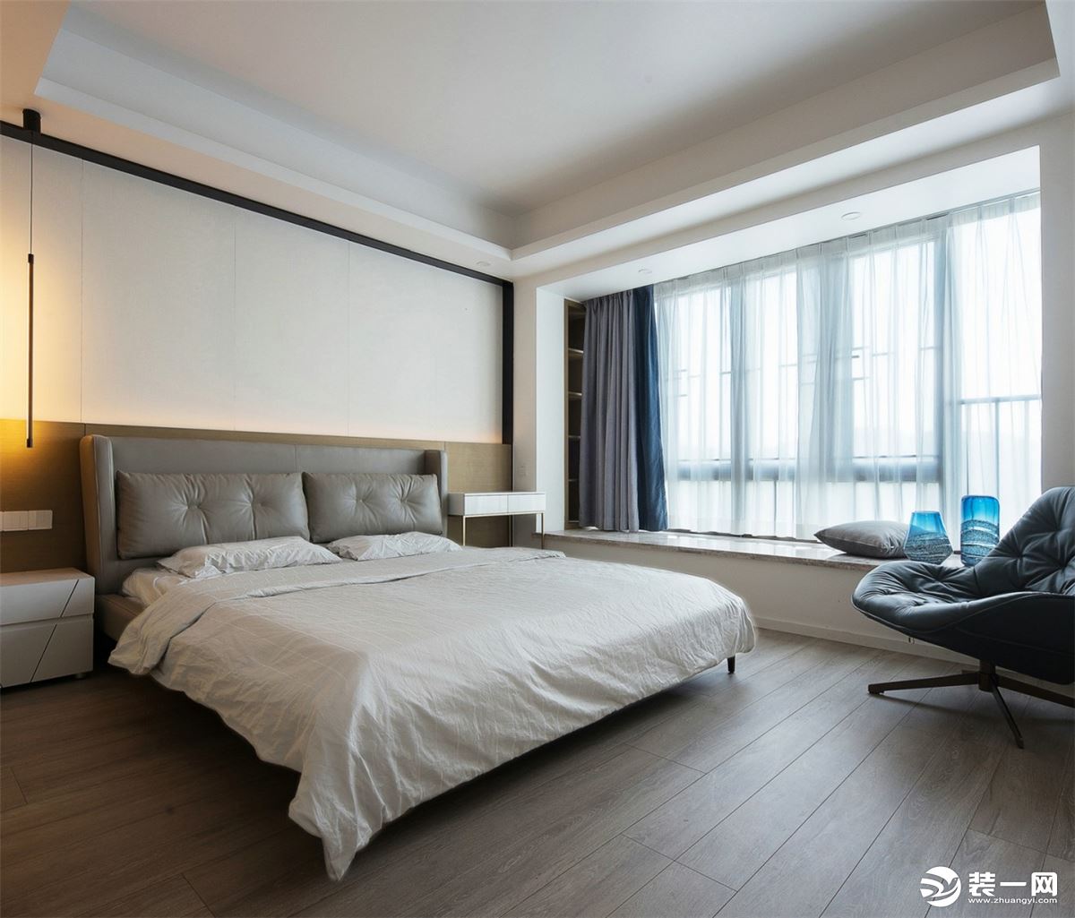 随动线进入卧室空间，氛围逐渐趋向平和。床头背景墙由米白色硬包和木色饰面组合而成，四周是黑色的细边铁艺