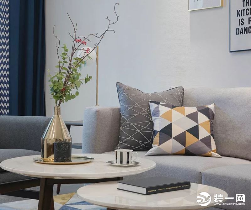 灰色的布艺沙发，搭配高矮的实木茶几，金色花瓶里蓬勃生长的绿植。