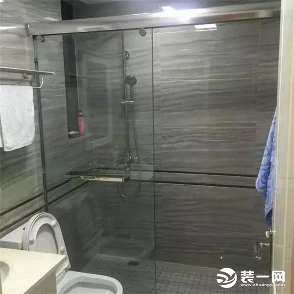 卫生间的淋浴区做了玻璃推拉门隔断，墙面和地面的瓷砖都是水泥灰纹，好打理，也很大气
