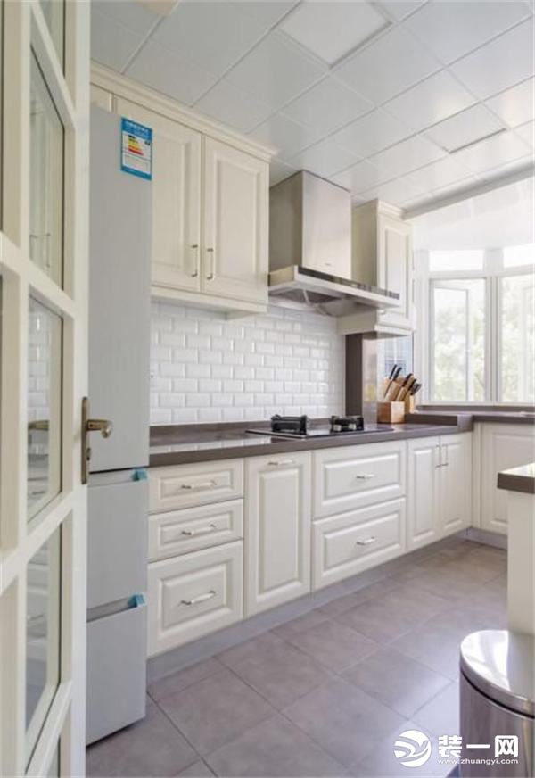 厨房没有做成深木色的整体橱柜，而是打造成清新的白色空间，橱柜按照空间的角度装成U字形