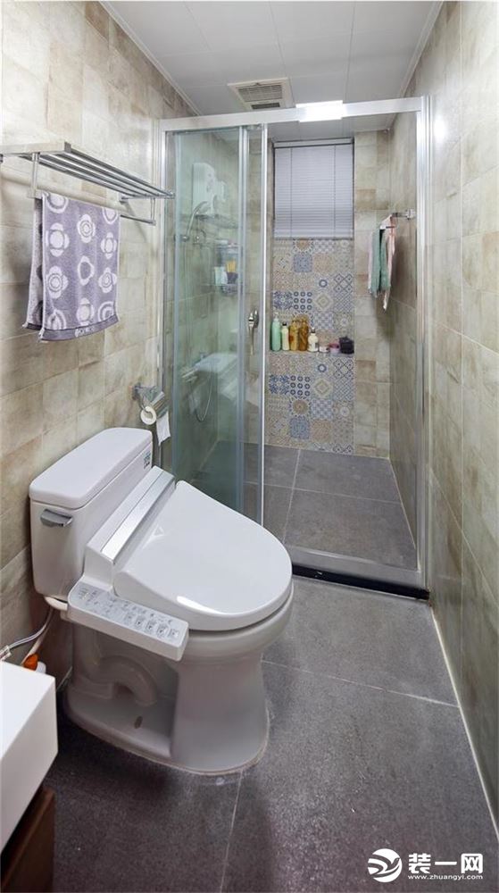 卫生间的瓷砖和厨房的一样的色调，淋浴间有花色瓷砖的点缀。安装的智能座便，长条形的卫生间显得井井有条