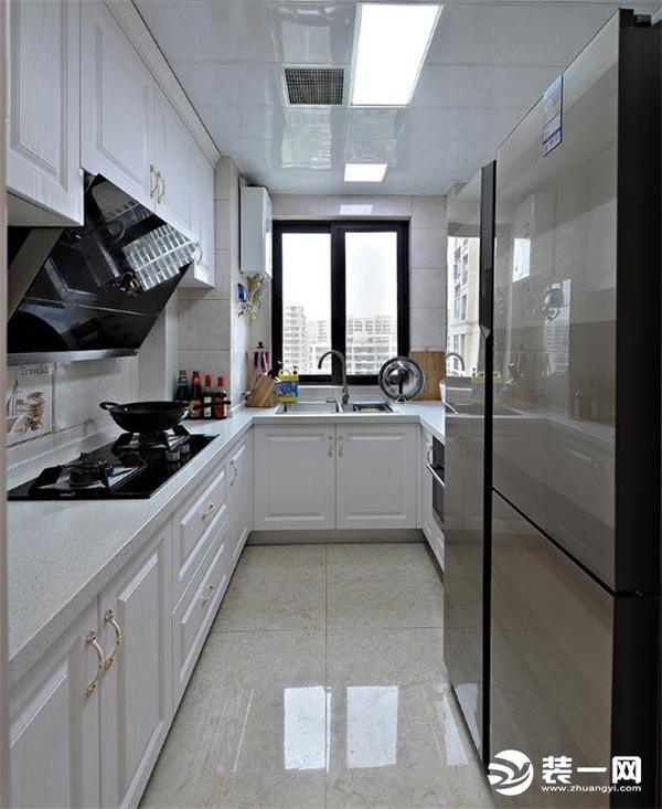 厨房是长条形的空间，打造U型整体橱柜，留出来放双开门冰箱的位置。