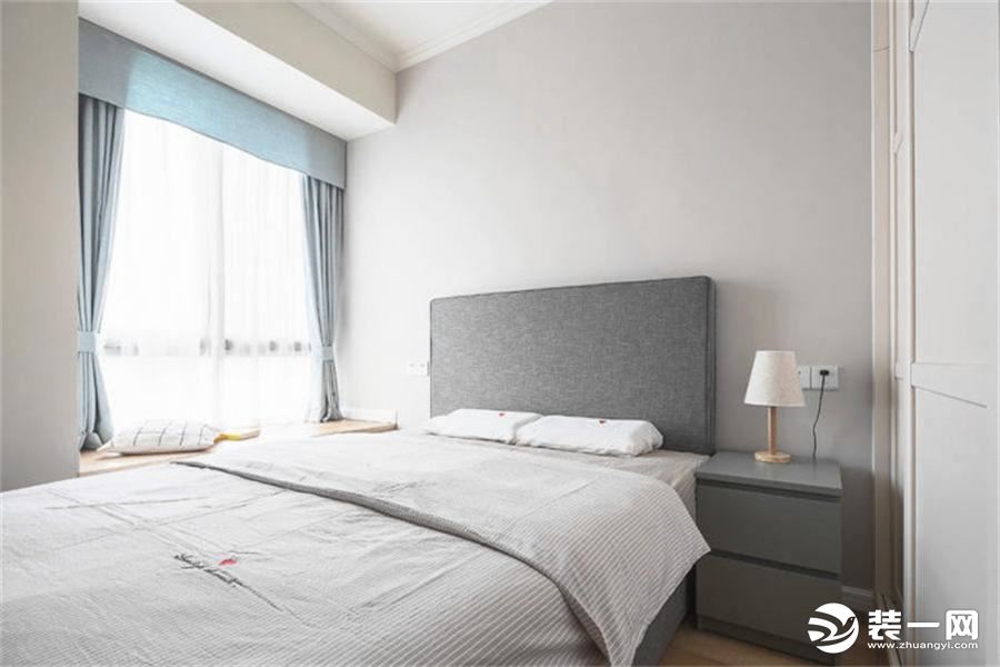 卧室是简单的白色色调为主，搭配灰色，突出了极简风格的装修，飘窗窗帘与客厅颜色和谐响应，可以饱览社区美