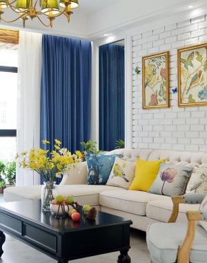 白色文化砖的墙面，米色的美式风格沙发，蓝色和亮黄色的艺术抱枕，让客厅的颜色都缤纷起来。