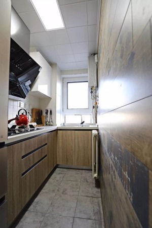 厨房是一个很长条的空间，半开放式，墙面都是做旧的斑驳的墙砖和地砖，实木的橱柜门板让房子北欧风格更清新