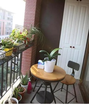 阳台上摆上了小店的一套休闲桌椅，有店里咖啡店的感觉，花草盆栽很多