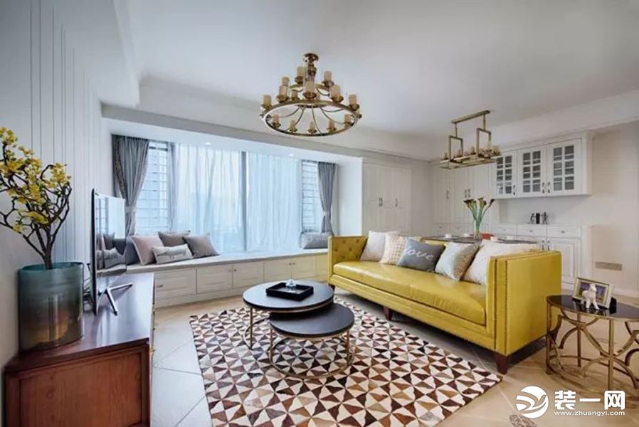 客厅与餐厅是个横厅格局的，居中位置摆一张素黄色的的皮沙发，地面搭配一块几何拼接图案的地毯