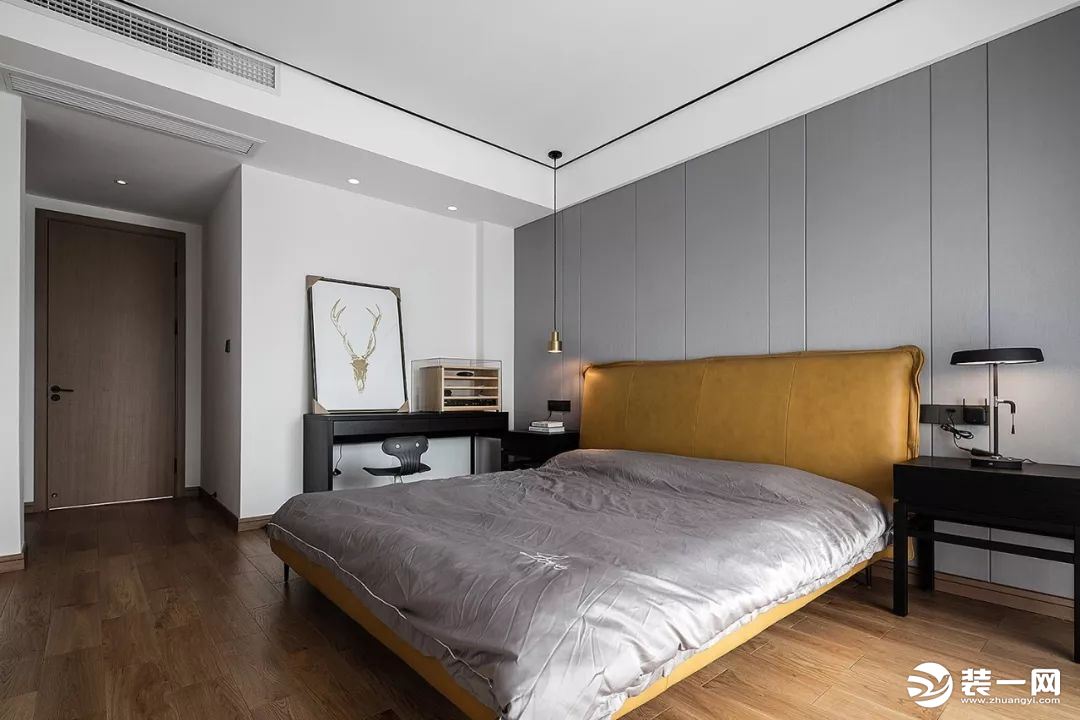 主卧室的床头做了浅灰色的硬包设计，搭配黄色的床和大气的黑色书桌、床头柜等，在简洁中展现贵气。