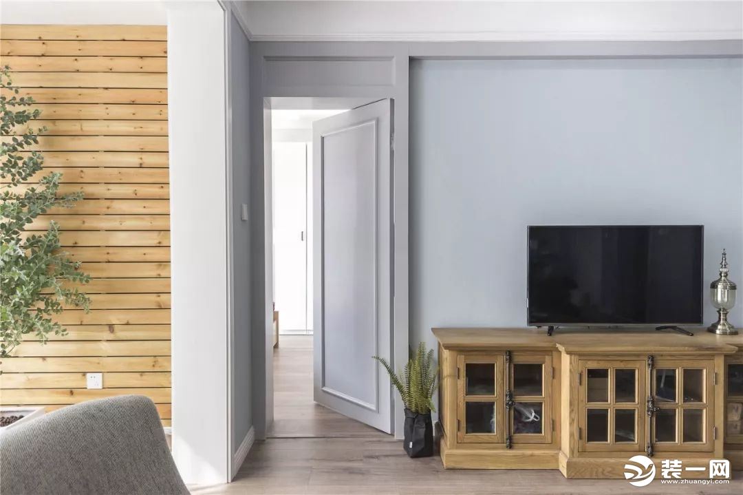 电视背景墙的两侧做对称的造型，这样可以把其中一侧的隐形门给藏起来。阳台的墙面铺贴了防腐木
