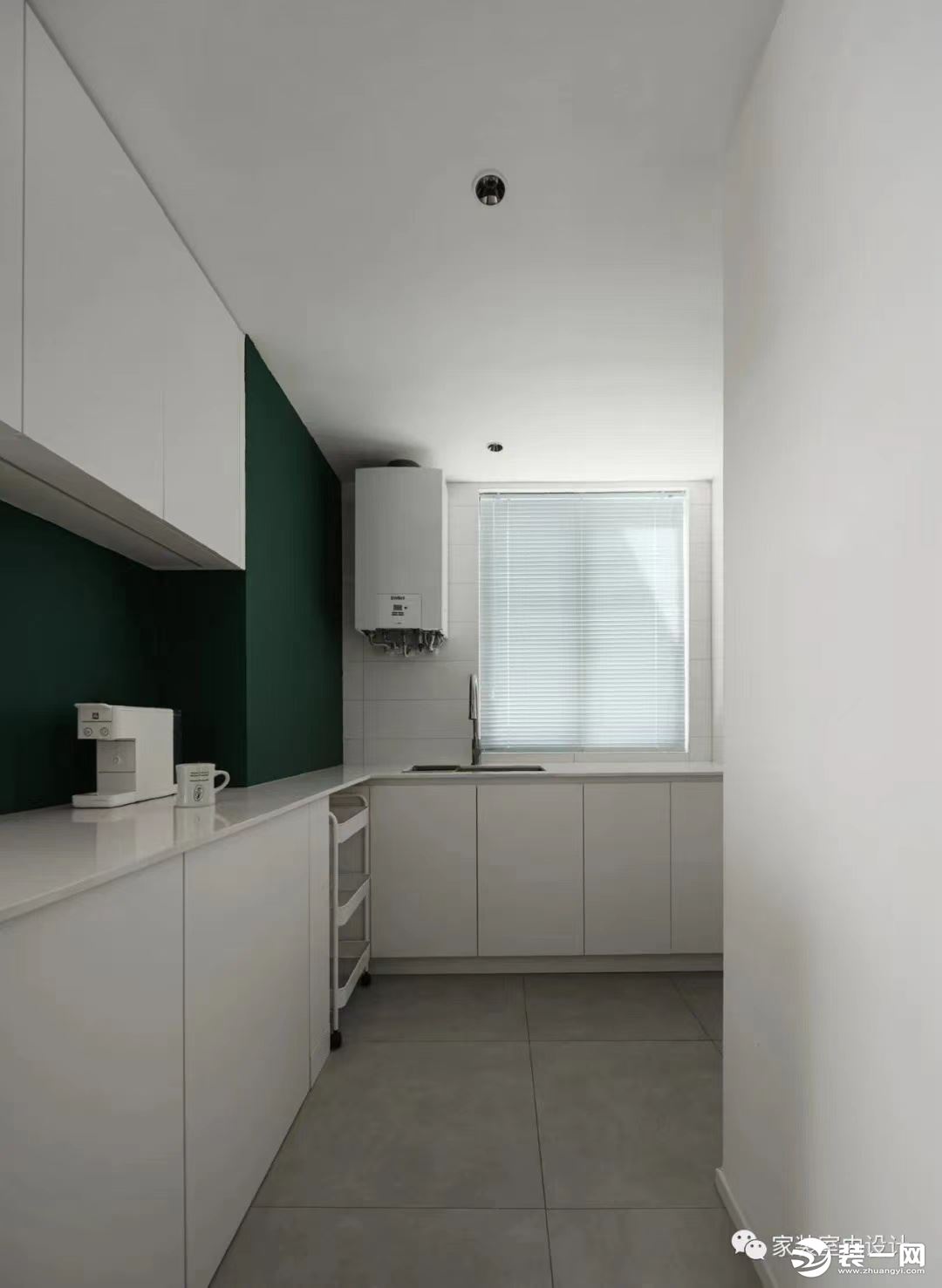 开放式厨房用瓷砖和墨绿色乳胶漆进行烹饪区和操作区的分割，通体白色的柜体弱化了墙体的拥堵感，让空间显得
