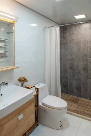 卫生间浴室柜柜门也是采用原木色，洗浴区域地砖采用仿木地板的瓷砖