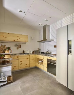 廚房內部做了L型的櫥柜。水泥質感的地磚搭配原木風的櫥柜，在簡潔輕松當中有著質樸鄉村的感覺。